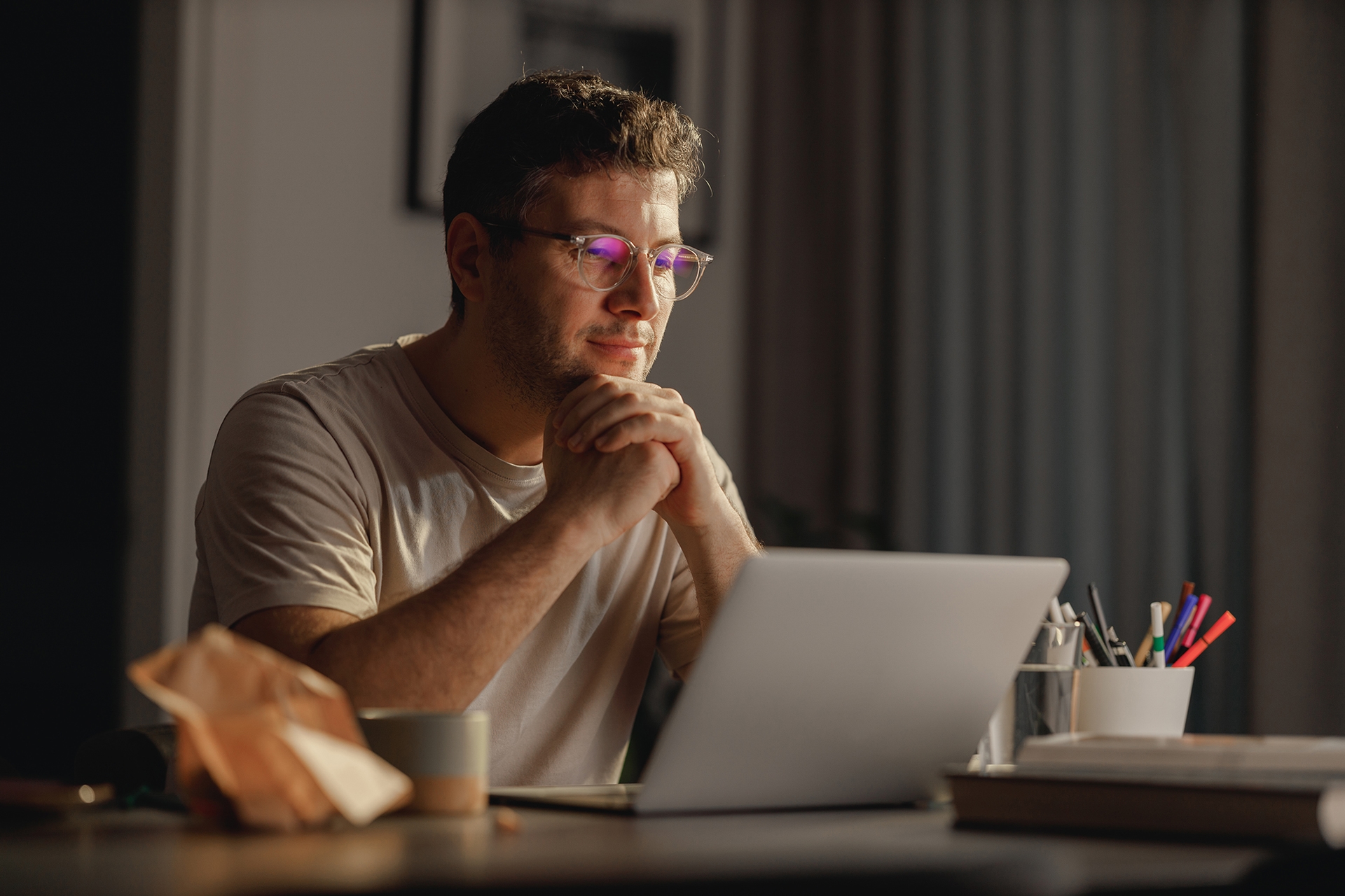 man with glasses at desk with laptop
