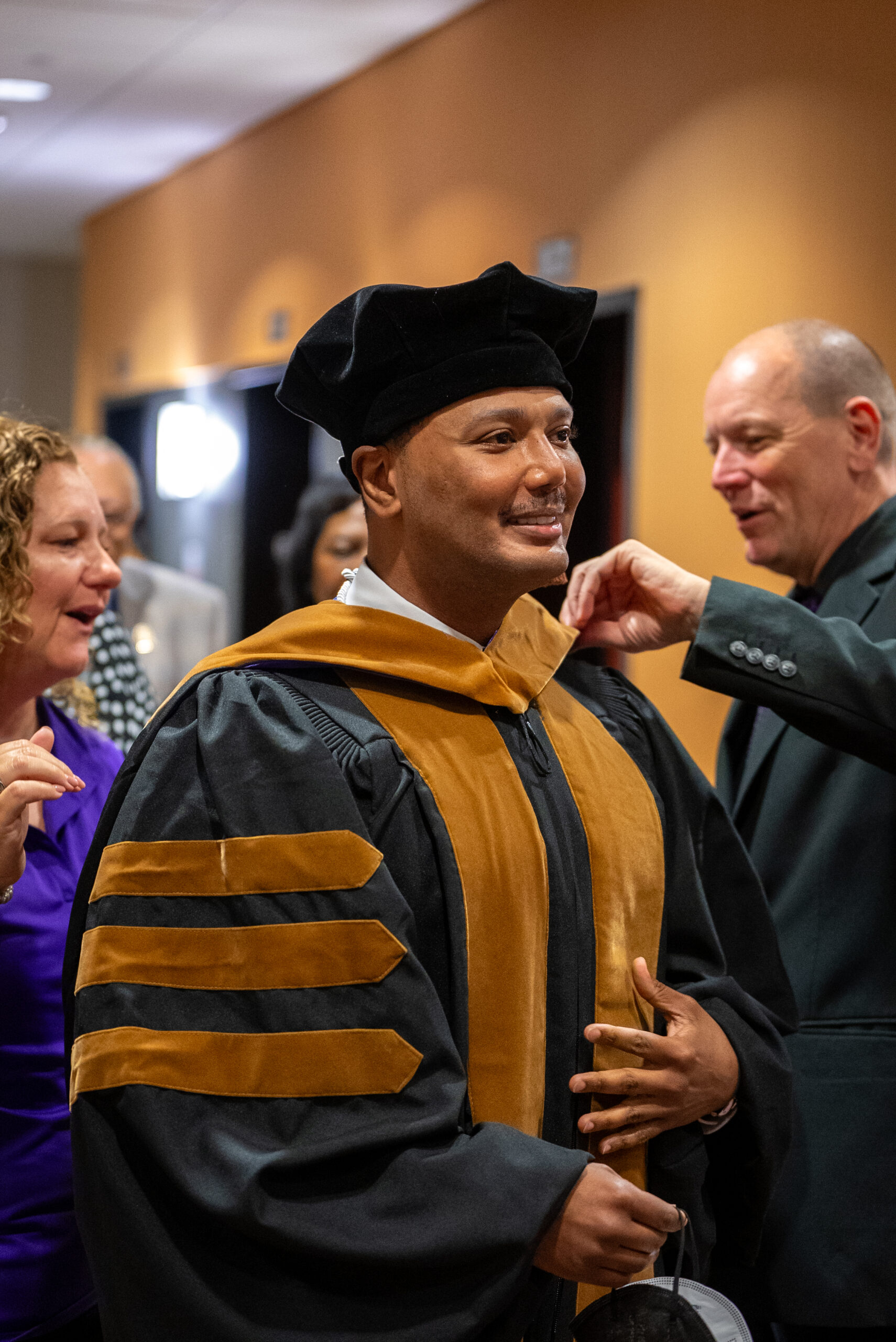 Bellevue staff help doctoral graduate adjust robe.