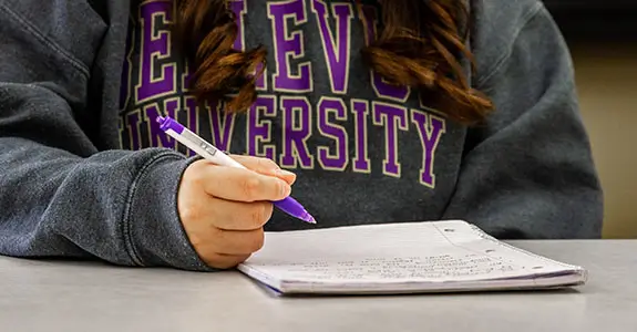 Close up of student writing in a notebook.