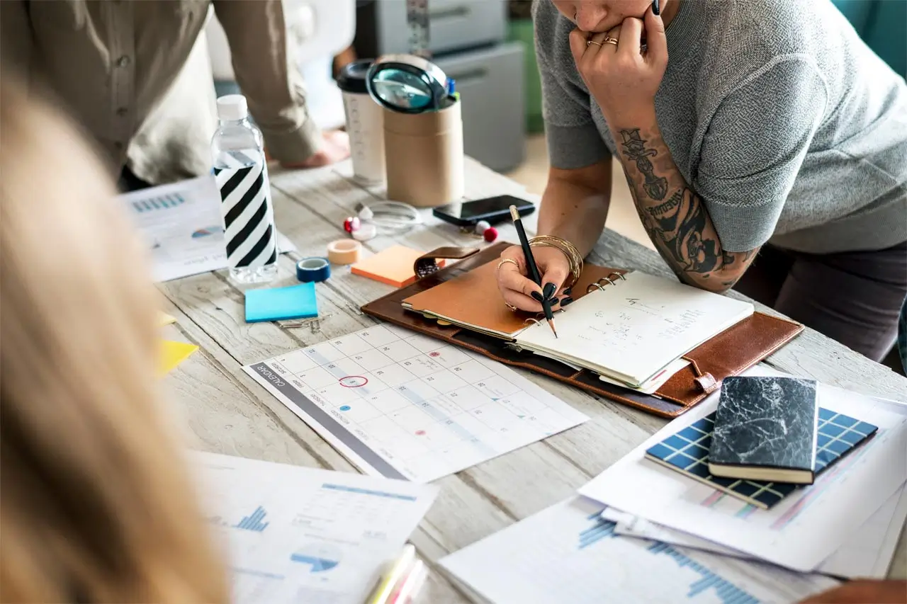 person at desk writing in notebook